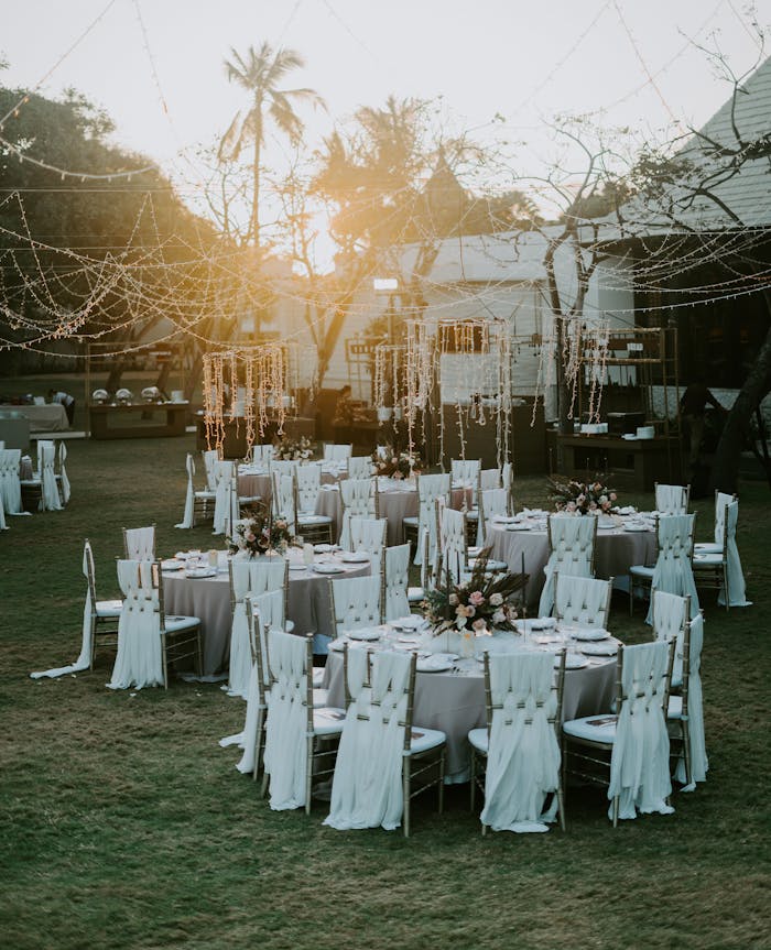 Charming sunset-lit outdoor wedding setup with adorned tables and chairs, perfect for celebrating love.